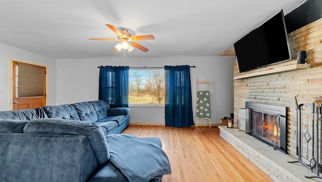 living room featuring ceiling fan, a fireplace, and light hardwood / wood-style floors