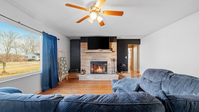 living room with wood-type flooring, a large fireplace, and ceiling fan