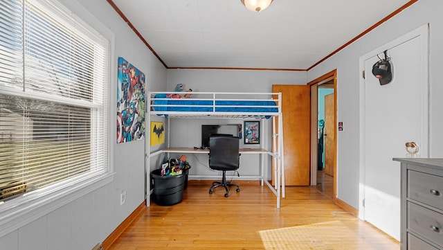 bedroom with built in desk, light wood-type flooring, and crown molding