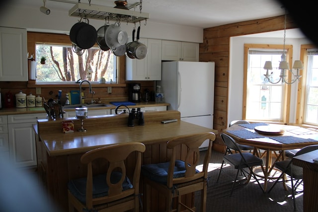 kitchen with white cabinets, a notable chandelier, white refrigerator, and sink