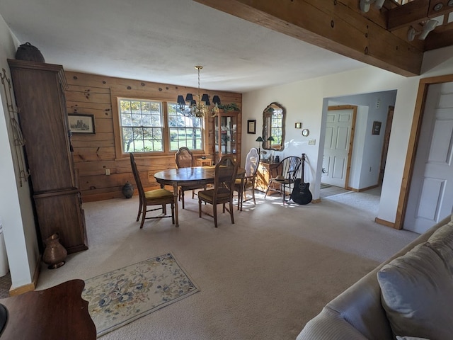 dining room with wood walls, light carpet, and an inviting chandelier