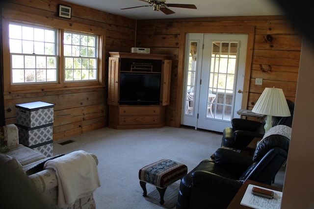 carpeted living room featuring ceiling fan and wood walls