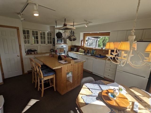 kitchen with sink, dishwasher, a center island, white cabinetry, and fridge