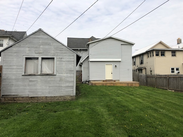 rear view of property featuring a lawn and a fenced backyard