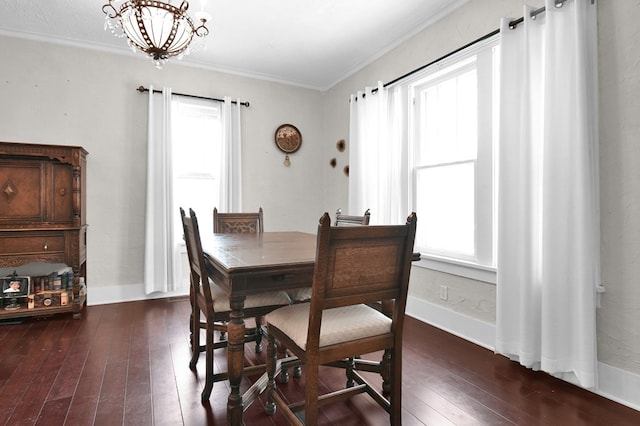 dining area with dark hardwood / wood-style flooring, ornamental molding, and an inviting chandelier