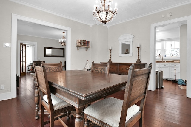 dining room featuring dark wood-type flooring, crown molding, sink, and a chandelier