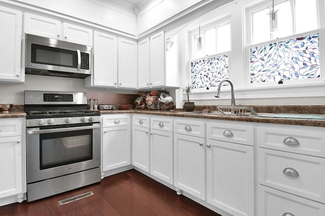 kitchen featuring dark hardwood / wood-style flooring, stainless steel appliances, white cabinetry, and sink