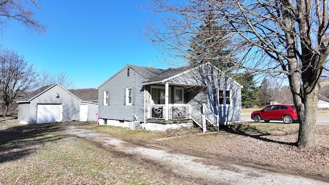 bungalow-style home with a detached garage, roof with shingles, covered porch, an outdoor structure, and driveway