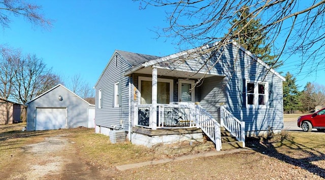 view of front of property with an outbuilding, driveway, roof with shingles, covered porch, and a garage