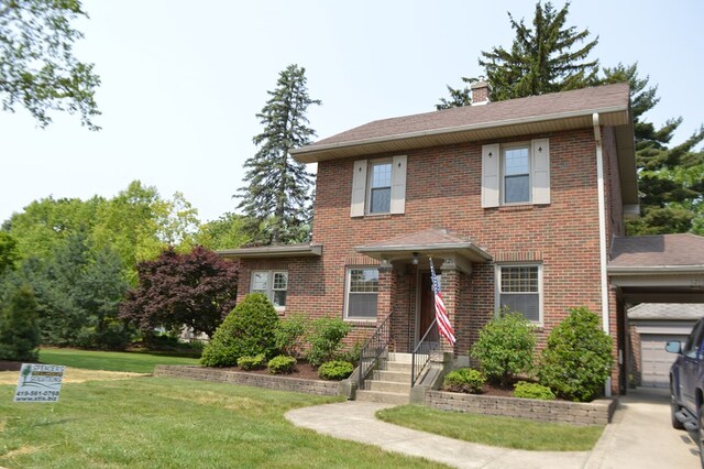 1211 S Sandusky Ave, Bucyrus, OH 44820 - view of front of house with a chimney, a front lawn, brick siding, and roof with shingles