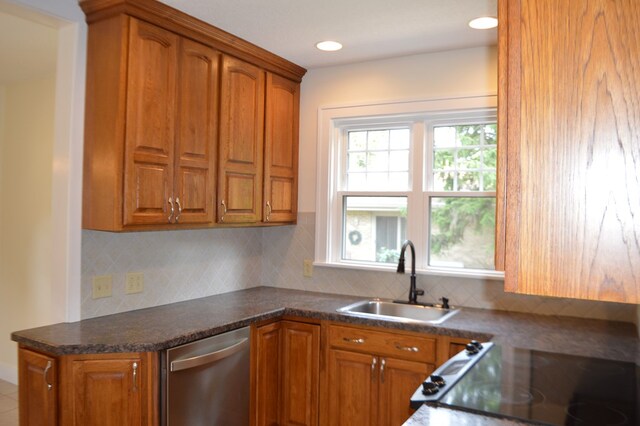 1211 S Sandusky Ave, Bucyrus, OH 44820 - kitchen with stainless steel dishwasher, a sink, brown cabinets, dark countertops, and decorative backsplash