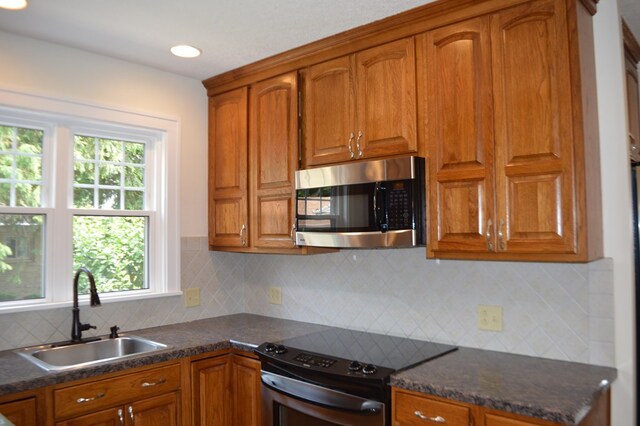 1211 S Sandusky Ave, Bucyrus, OH 44820 - kitchen with stainless steel microwave, electric range oven, a sink, brown cabinetry, and dark countertops
