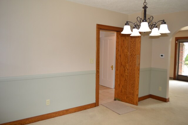 1211 S Sandusky Ave, Bucyrus, OH 44820 - empty room featuring arched walkways, carpet, a chandelier, and baseboards