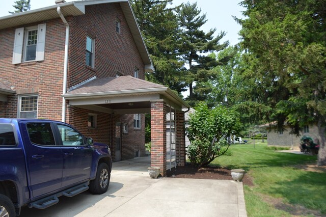 1211 S Sandusky Ave, Bucyrus, OH 44820 - view of property exterior with brick siding, a lawn, driveway, and an attached carport