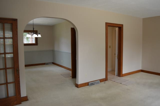 1211 S Sandusky Ave, Bucyrus, OH 44820 - carpeted empty room with arched walkways, a chandelier, and baseboards