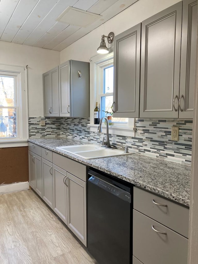 kitchen with black dishwasher, light hardwood / wood-style flooring, plenty of natural light, and sink