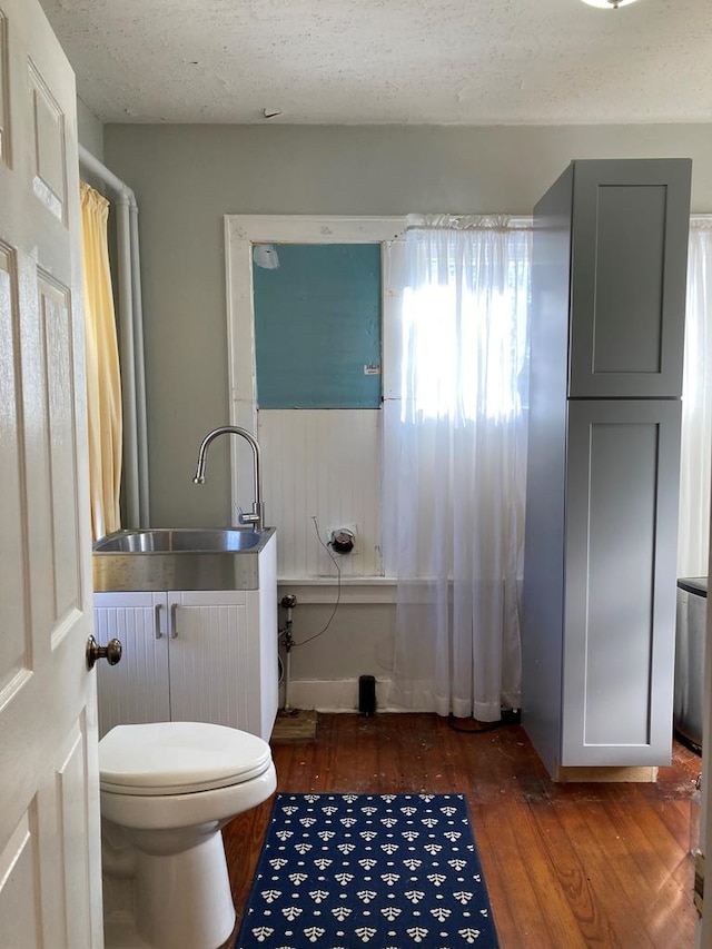 bathroom with toilet, sink, a textured ceiling, and hardwood / wood-style flooring