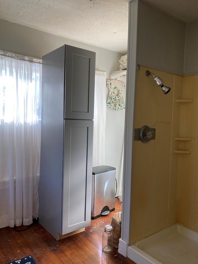 bathroom with a shower, a textured ceiling, and hardwood / wood-style flooring