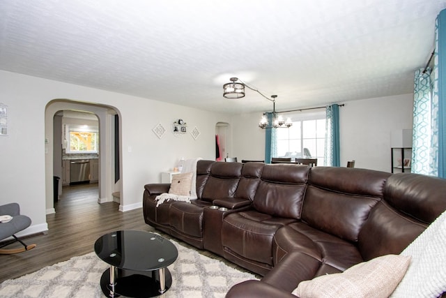 living area featuring arched walkways, baseboards, wood finished floors, and a chandelier
