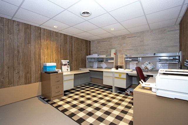 office featuring visible vents, wood walls, built in desk, and a drop ceiling