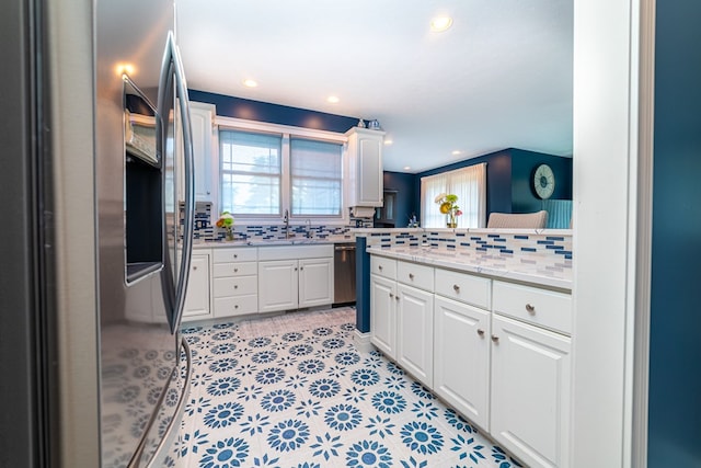 kitchen featuring white cabinets, sink, decorative backsplash, light stone counters, and stainless steel appliances