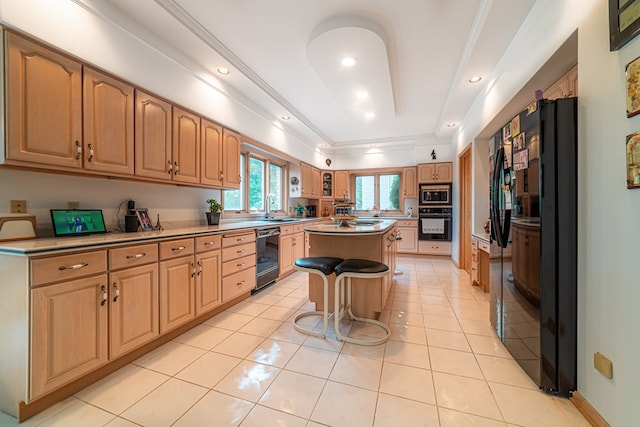 kitchen featuring black appliances, a raised ceiling, sink, a kitchen island, and a kitchen bar