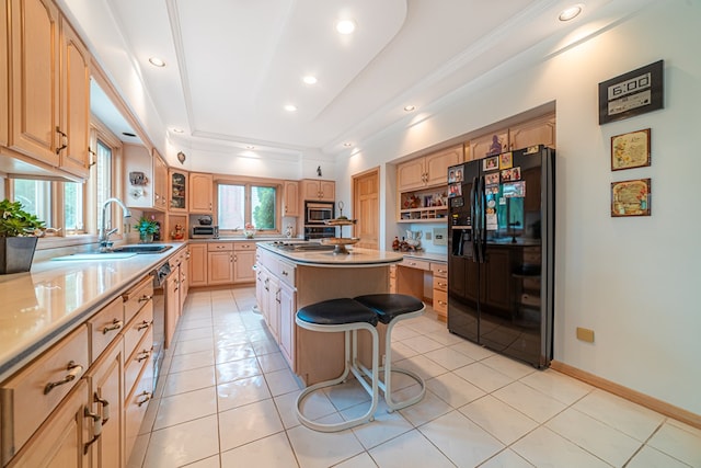 kitchen featuring a raised ceiling, black appliances, a center island, a breakfast bar area, and light tile patterned flooring