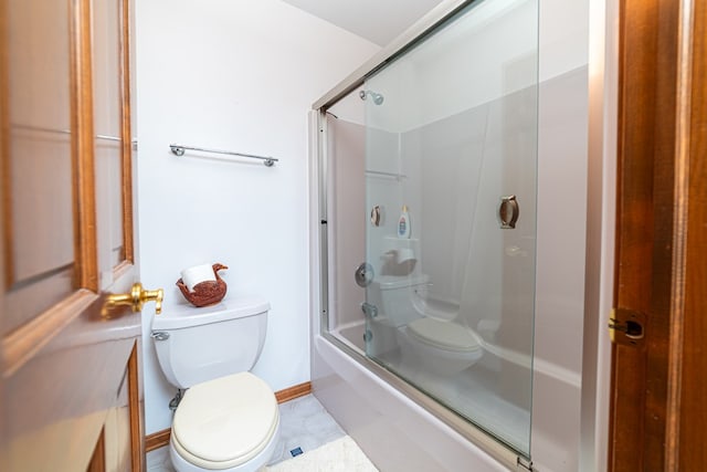 bathroom featuring toilet and bath / shower combo with glass door