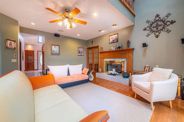 living room featuring ceiling fan, a high end fireplace, and light hardwood / wood-style floors