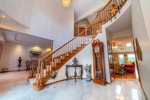 staircase featuring a high ceiling and ceiling fan with notable chandelier