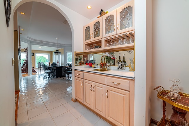 bar featuring light tile patterned floors, hanging light fixtures, light brown cabinetry, and sink