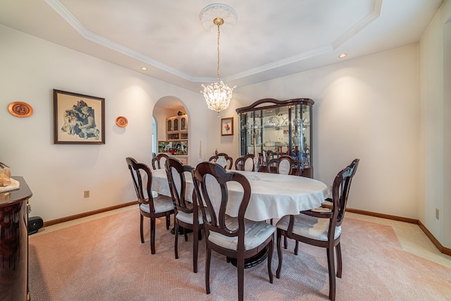 dining space featuring light carpet, a raised ceiling, a notable chandelier, and crown molding