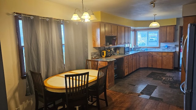 kitchen with stainless steel appliances, dark wood-type flooring, pendant lighting, and a chandelier