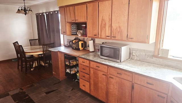 kitchen with dark wood-type flooring, a notable chandelier, and decorative light fixtures