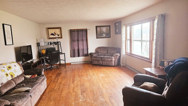 living room with hardwood / wood-style flooring, baseboard heating, and a textured ceiling