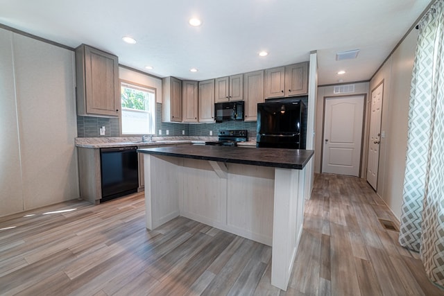 kitchen featuring light wood-type flooring, a center island, and black appliances