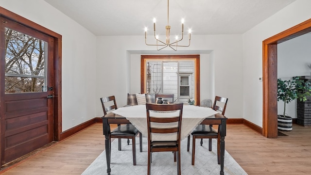 dining room with a notable chandelier, light hardwood / wood-style flooring, and a textured ceiling