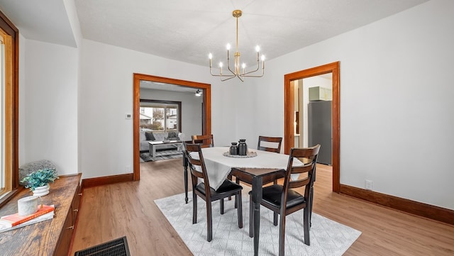 dining room featuring a notable chandelier, a textured ceiling, and light wood-type flooring