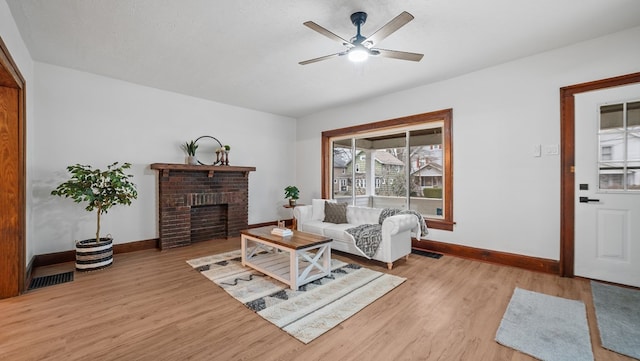 living room featuring a textured ceiling, a brick fireplace, and light wood-type flooring