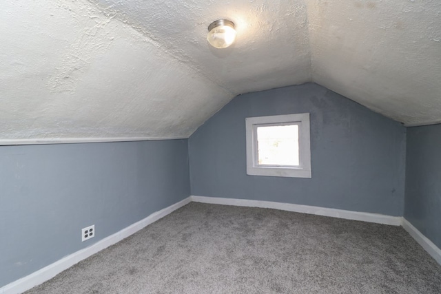 additional living space with carpet flooring, lofted ceiling, and a textured ceiling