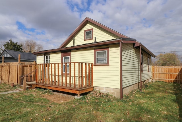 back of property with a yard and a wooden deck