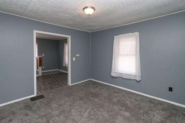 spare room with a textured ceiling and dark carpet