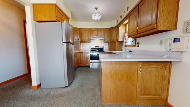 621 Heidi Ln, Mansfield, OH 44904 - kitchen with freestanding refrigerator, stainless steel range with electric cooktop, under cabinet range hood, a peninsula, and brown cabinetry
