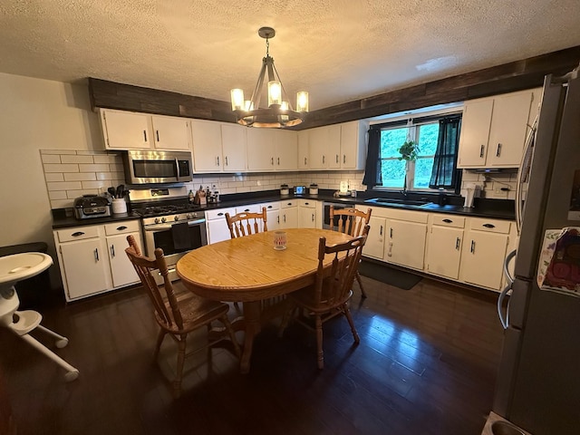 108 Melcher Blvd, Bucyrus, OH 44820 - kitchen with stainless steel appliances, a textured ceiling, dark wood-style floors, a chandelier, and white cabinets