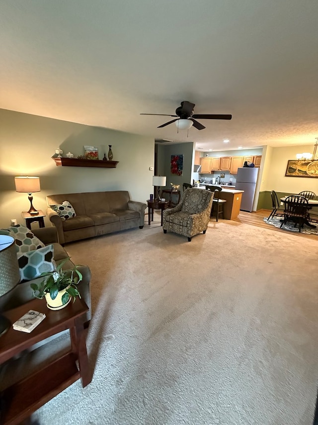 living area featuring light colored carpet and a ceiling fan