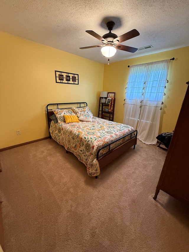 bedroom featuring ceiling fan, carpet flooring, visible vents, and a textured ceiling