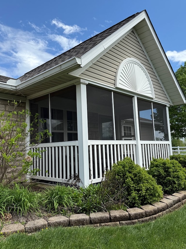 view of property exterior featuring a sunroom and a shingled roof