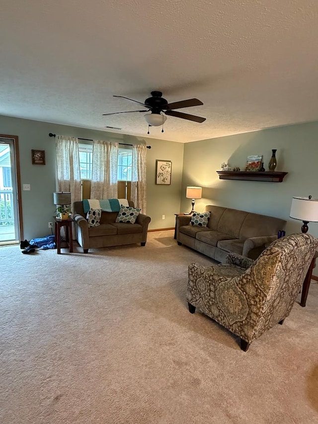 living room featuring carpet flooring, a textured ceiling, baseboards, and ceiling fan