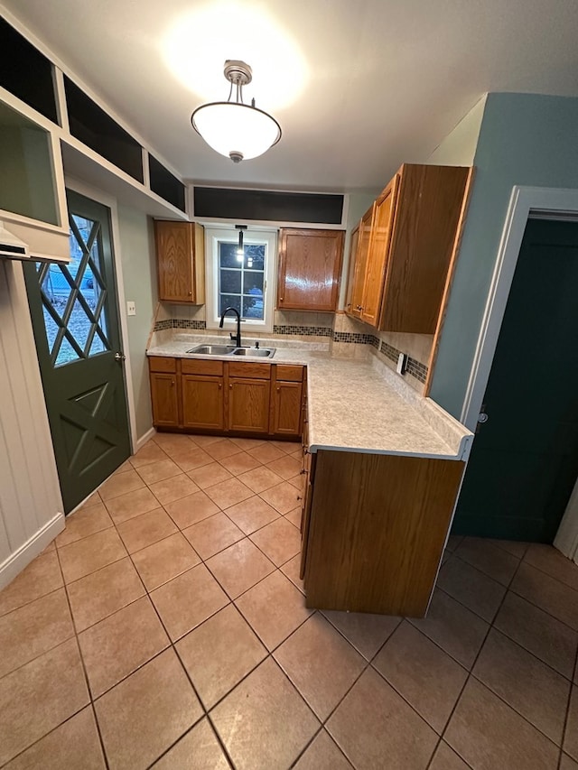 kitchen with brown cabinetry, light countertops, a sink, and light tile patterned flooring