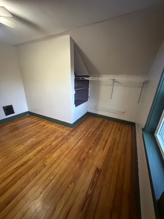 additional living space featuring lofted ceiling, baseboards, wood finished floors, and visible vents
